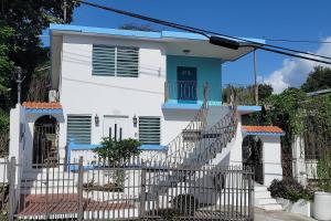a white house with a blue door and stairs at Above The Plaza 4 (6 guest) in Rincon
