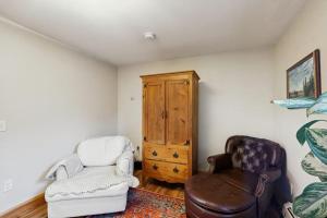 a living room with two chairs and a cabinet at 2-story apartment steps from the harbor & downtown in Boothbay Harbor