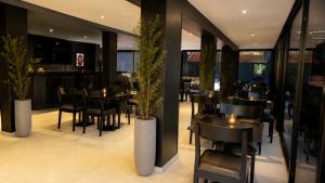 a restaurant with black chairs and tables and plants at Stream Suites Pinamar in Ostende