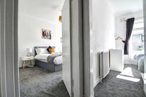 a white bedroom with a bed and a window at Kingspark Apartment Apartment in Glasgow