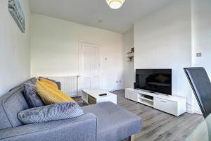 a living room with a couch and a flat screen tv at Kingspark Apartment Apartment in Glasgow
