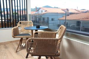 two wicker chairs and a table on a balcony at D&C Premium Suites in Pefkochori