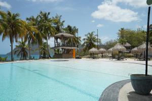 a swimming pool with chairs and straw umbrellas at Suite Blue Diamond vue mer in Le Diamant
