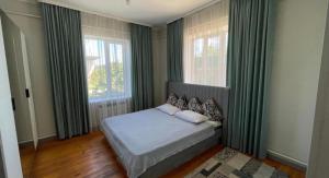 a bedroom with a bed and two windows at Guest Home in Jalal-Abad