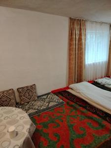 a bedroom with a bed and a table and a window at Чырак in Ak-Osten