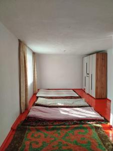 two beds in a room with a rug on the floor at Чырак in Ak-Osten