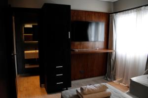 a black cabinet with a tv in a bedroom at Stream Suites Pinamar in Ostende +28 photos