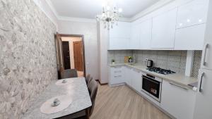 a kitchen with white cabinets and a table with chairs at Аэропорт Комфорт in Chişinău