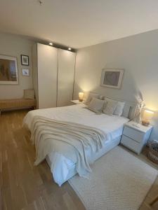 a bedroom with a large white bed with two lamps at Modern apartment with a private garage in Lørenskog Oslo in Lorenskog