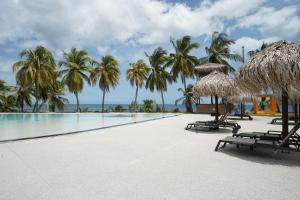 a pool with chairs and umbrellas and palm trees at Suite Sabi Vue Mer in Le Diamant