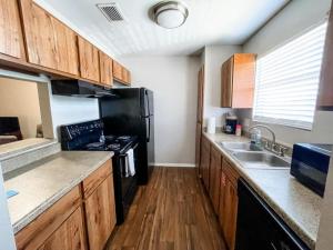 a kitchen with wooden cabinets and a black refrigerator at 10 Min to Downtown - Pet-friendly, TV with Parking in Robstown