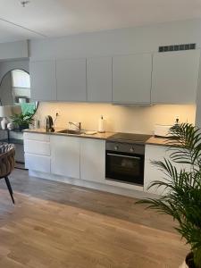 a kitchen with white cabinets and a black stove at Modern apartment with a private garage in Lørenskog Oslo in Lorenskog