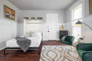 a bedroom with a white bed and a green chair at Walk/ Bike everywhere from this Historic Chic Studio in Columbus