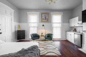 a bedroom with a bed and two chairs and a kitchen at Walk/ Bike everywhere from this Historic Chic Studio in Columbus