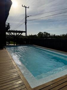 a swimming pool on a wooden deck with the sun in the background at Apartamento 313 Bobz Concept in Cajueiro