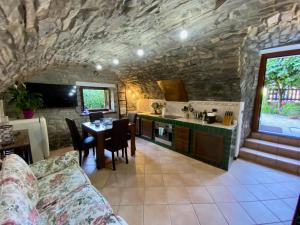 a kitchen and dining room with a stone wall at Castello Cottage in Argegno