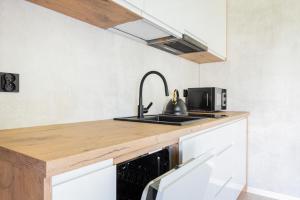 a kitchen with a sink and a microwave at Domki u Basi - 250m do Plaży - Idealne dla Rodzin in Karwia
