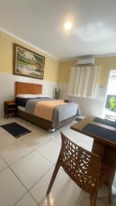 ein Schlafzimmer mit einem Bett, einem Tisch und einem Stuhl in der Unterkunft Kitnet 17D in São Luís