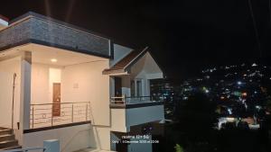 a white house with a balcony at night at Mithra Cottages individual Villa in Ooty