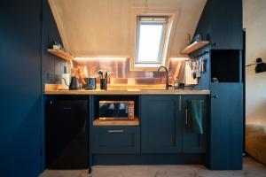 a kitchen with blue cabinets and a microwave at Hillend by Wigwam Holidays in Todmorden