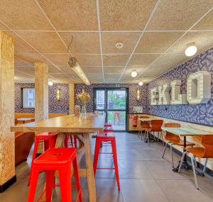 a restaurant with red stools and a table and chairs at UNISOTEL Le Havre in Le Havre