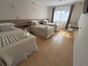 a hotel room with two beds and a window at Hotel Frontera in Antofagasta