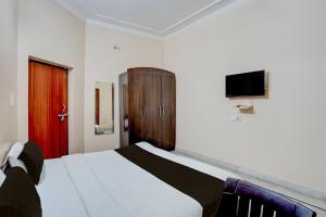 a bedroom with a bed and a tv on the wall at Hotel O Hotel Brijwasi in Lucknow
