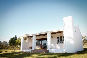 a white house on a grassy field at Kweekkraal Guest Farm in Riversdale
