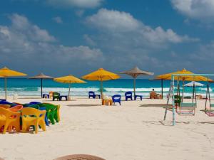 a beach with chairs and umbrellas on the sand at Aghadir Village قرية اغادير in El Alamein