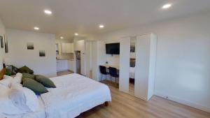 a bedroom with a large white bed and a kitchen at Hygge Hus Hotel in Andrews