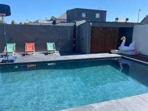 a swimming pool with two chairs and a swan at Silver in Quessoy