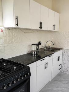a kitchen with white cabinets and a sink and a stove at Utsera Veranda in Utsera