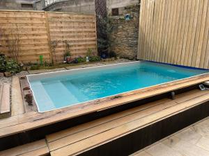 a swimming pool in a backyard with a wooden fence at La maison aux volets bleus in Laval
