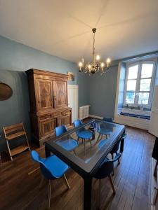 a dining room with a table and blue chairs at La maison aux volets bleus in Laval