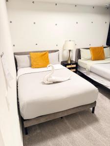 a bedroom with two beds and a swan on the bed at Emerald - 10mins from Stampede Park in Calgary