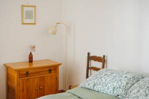 a bedroom with a bed and a lamp and a wooden dresser at Le Triangle de l'île - Chambre La Jardin in Saint-Laurent-de-l'ile d'Orleans
