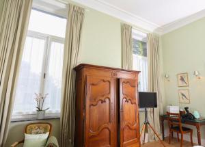 a large wooden cabinet in a room with a table at Le Jardin des Roses Mons & Pairi Daiza proches in Dour