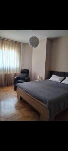 a bedroom with a large bed and a blue chair at Panorama View in Niš