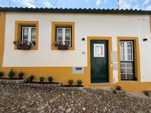 a house with three windows and a green door at Casa das Flores in Sardoal