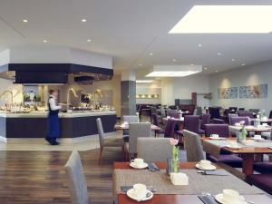 a person standing in a restaurant with tables and chairs at Mercure Düsseldorf Kaarst in Kaarst