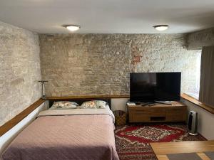 a bedroom with a bed and a flat screen tv at Old town Stylish Stonehouse Kauba 6a in Kuressaare