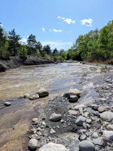 a river with rocks and trees in the background at Campagne Vallauris gites in Vaumeilh