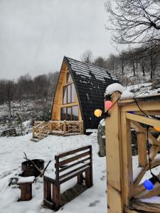 a wooden cabin in the snow with a bench at Andi's Home in Bogë +13 photos