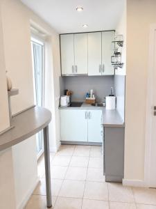 a kitchen with white cabinets and a tiled floor at Kopų gatvės studija Nidoje in Nida
