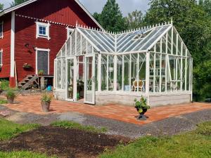 a greenhouse in front of a red barn at Humlebo stuga med bastu in Söderköping