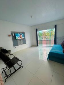 a bedroom with a tv and a bed and a chair at Beach House in Barra dos Coqueiros