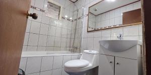 a bathroom with a toilet and a sink and a tub at Alojamiento Zapallar in Curicó +21 photos