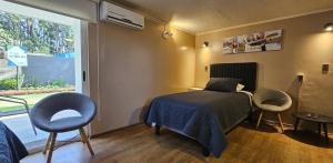 a bedroom with a bed and two chairs and a window at Alojamiento Zapallar in Curicó