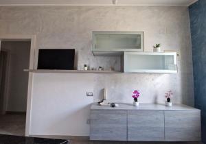 a living room with a desk with a television and flowers at Domus Enricucciu in Lanusei