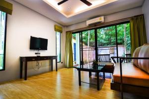 a living room with a couch and a tv at Cocoville Phuket - SHA Plus in Chalong